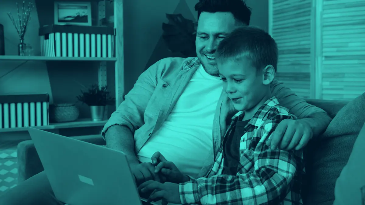 Ayah dan anak memakai laptop bersama di rumah